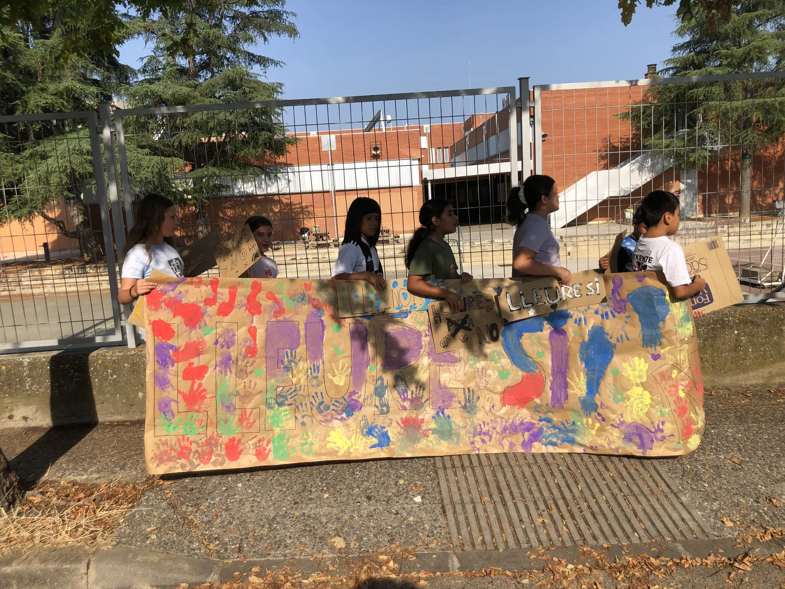 Infants mostren un mural pintat durant les activitats del Casal Migdia d’agost
